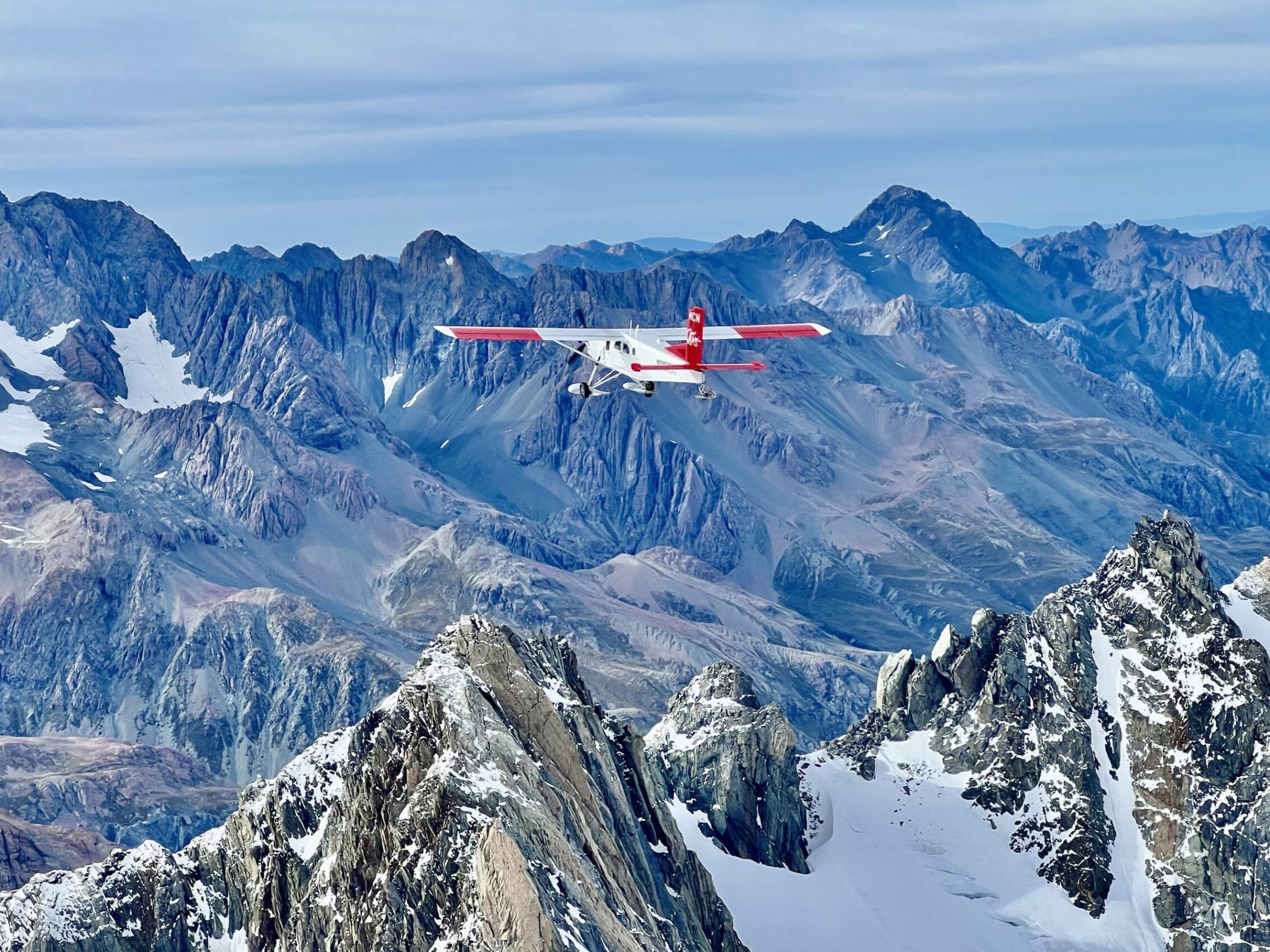 White ski plane flies across snowy mountain range in Mountain Cook