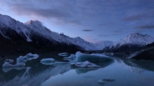 A mountain covered with snow surrounded by water
