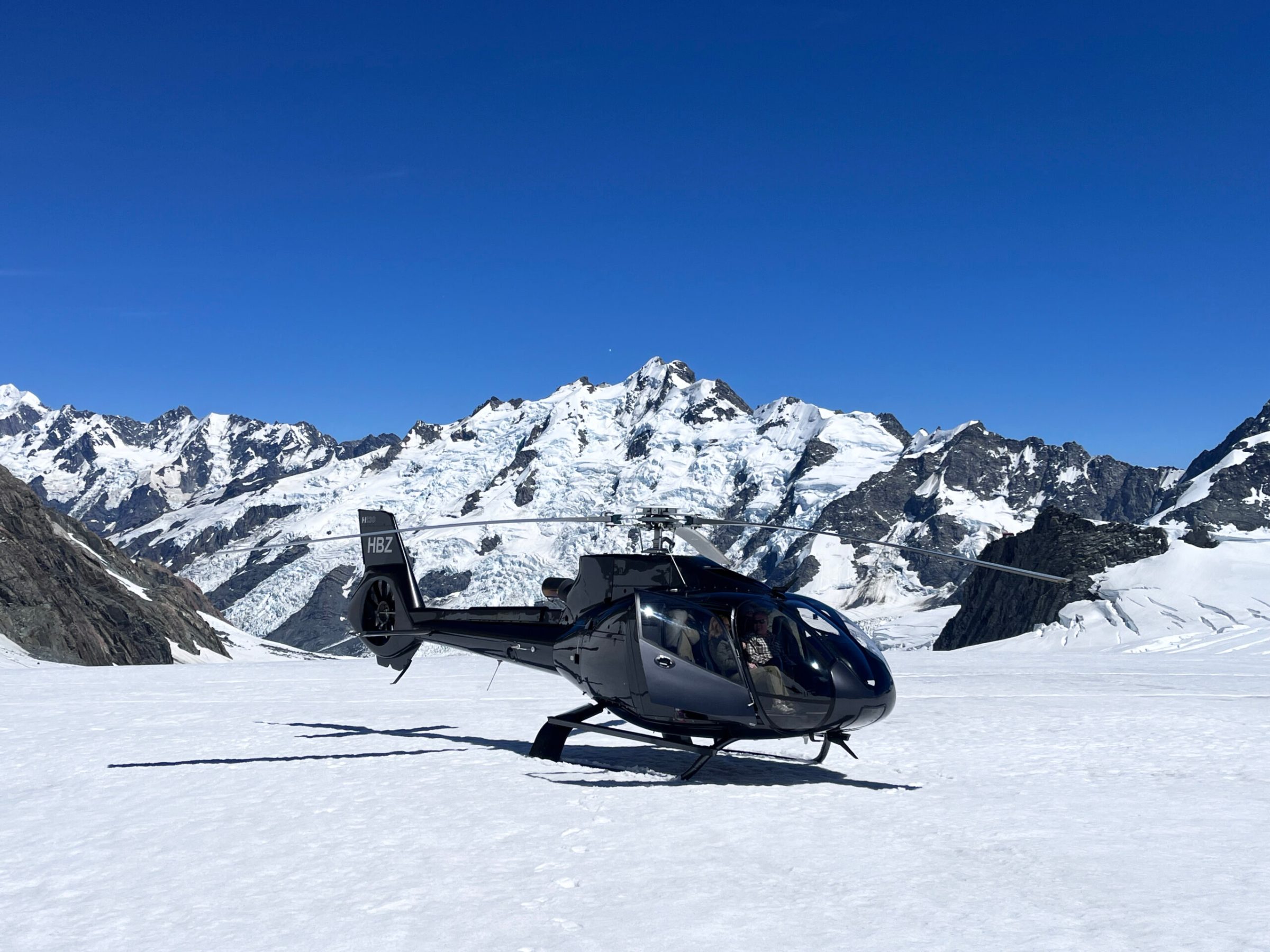 Inflite helicopter lands on the snow of the tasman glacier with mountains in view