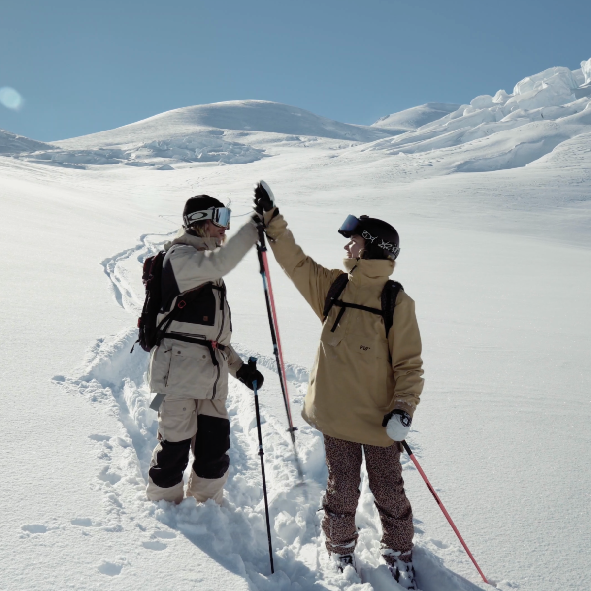 two skiiers high five after ski the tasman on the snow