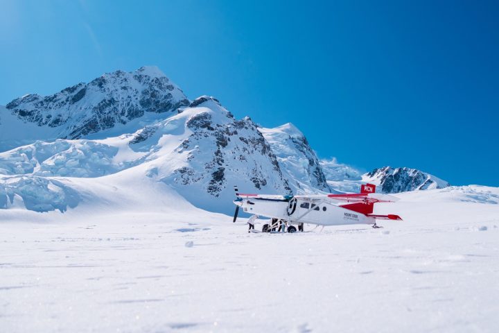 Ski plane on snowy mountain landscape under clear blue sky.