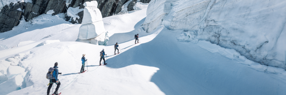 Group of climbers ascending a snowy mountain path with ice formations.