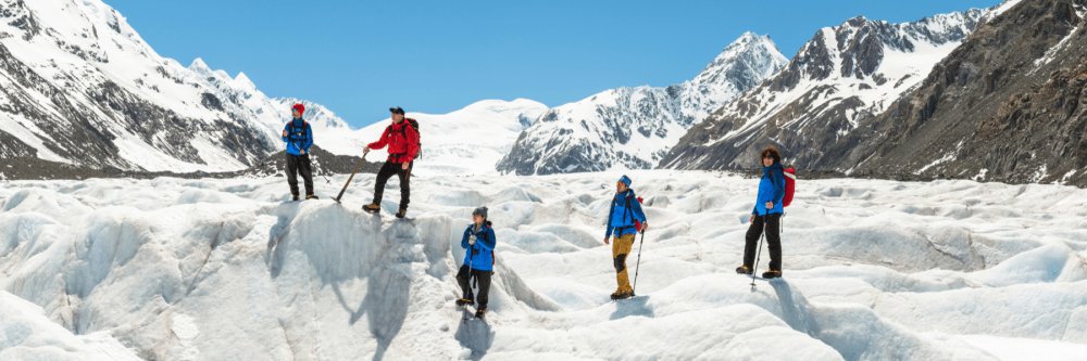 Group of five people hiking on a snowy mountain glacier.